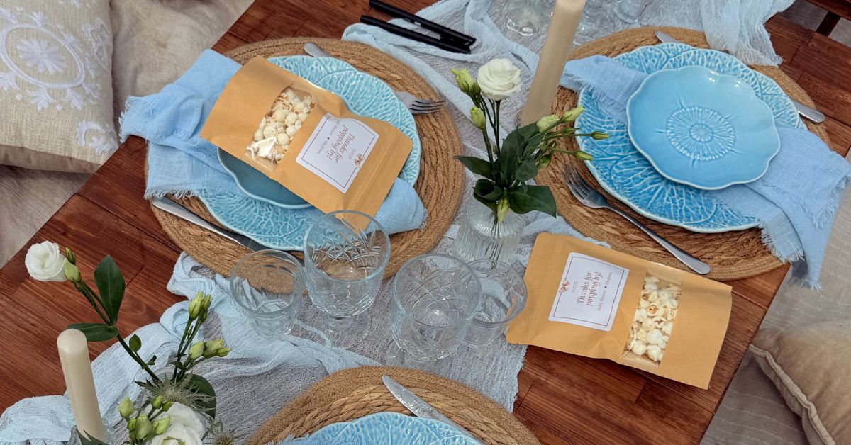 Stijlvolle babyshower tafel met blauwe serviezen, kraft zakjes en bloemen